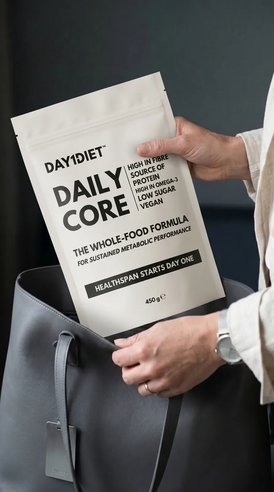 Day1Diet Daily Core pouch held in hand beside a tote bag, the matte pack and label true to the product