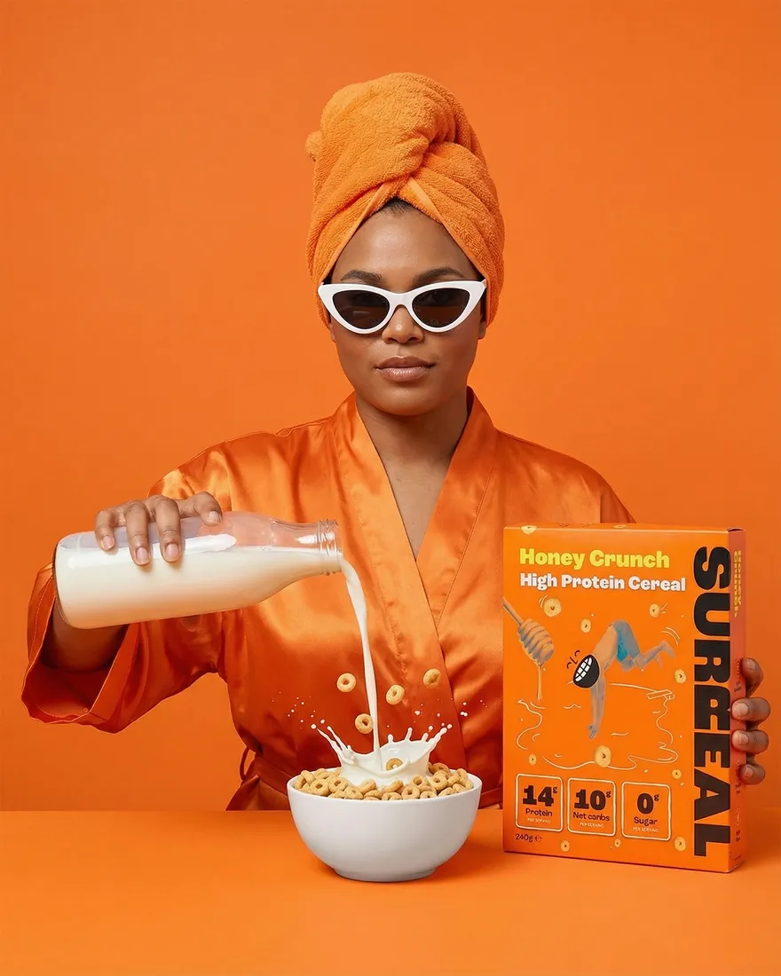 In-situ image of a model in white sunglasses pouring milk alongside a cereal carton on an orange backdrop